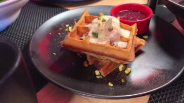 Dondurma ve reçelli waffle, siyah bir restoranda sabah kahvaltısı. Yüksek kalite 4k görüntü