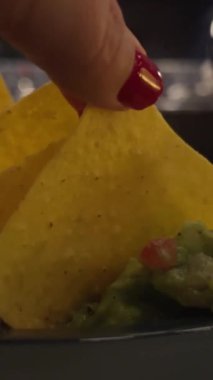 Salsa sosu ve soslu guacamole sosu, servis masasında nacho cipsi. Avokado toplayan el.