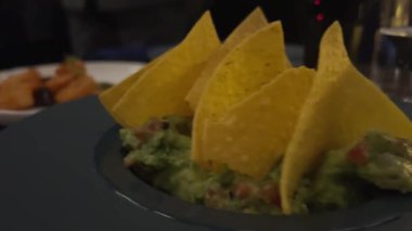 Meksika guacamole ve tortilla cipsi, nachos, yavaş dönen kameranın üst görüntüsü, ulusal tatiller için tipik yemek, cinco de mayonez. Yüksek kalite 4k görüntü