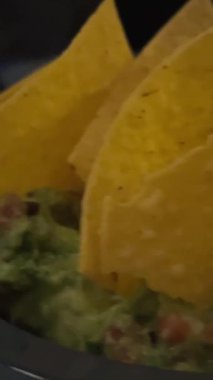 Meksika guacamole ve tortilla cipsi, nachos, yavaş dönen kameranın üst görüntüsü, ulusal tatiller için tipik yemek, cinco de mayonez. Yüksek kalite 4k görüntü