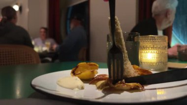 Kadın çatal ve bıçakla doldurulmuş enginardan bir parça alıyor ve yiyor. Restoran. İzmir, Türkiye. Yenilebilir çiçeğin güzel sunumu