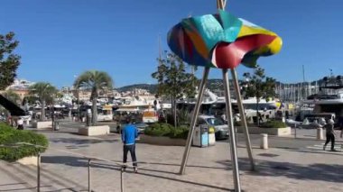 Cannes, Fransa 'da soyut heykel. Canlı, soyut bir heykel, açık mavi gökyüzü ve limanda demirlemiş teknelerle limanda gururla duruyor. France Cannes 11.2024