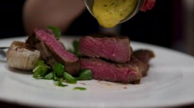 Yemek videosu yavaş çekimde. Fırfırlı bifteğe sos döken şef. Restoran yemeği servisi. Ağır çekimde akıcı soslu ızgara barbekü dana eti. - Evet. Yüksek kalite 4k görüntü