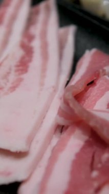 Esmer arka planda baharat ve otlarla dilimlenmiş taze çiğ domuz pastırması. Yüksek kalite 4k görüntü