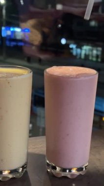 Pencere kenarındaki buzlu içecek, cam bardaklara pipetler, plastik pipetler ve şehrin kokteylleri. Yüksek kalite 4k görüntü