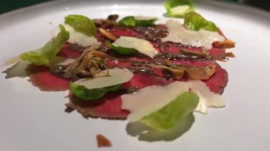 Şef yeşillikler, baharatlar, mantarlar, dekorasyonlar seriyor. Modern güzel yemekler. Mutfak işletmelerini ara. Bulanık arka plan restoranı. Parmesanlı Carpaccio ve beyaz tabakta otlar.