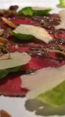 Şef yeşillikler, baharatlar, mantarlar, dekorasyonlar seriyor. Modern güzel yemekler. Mutfak işletmelerini ara. Bulanık arka plan restoranı. Parmesanlı Carpaccio ve beyaz tabakta otlar.
