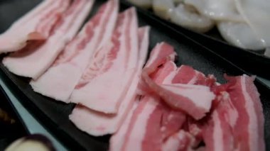 Esmer arka planda baharat ve otlarla dilimlenmiş taze çiğ domuz pastırması. Yüksek kalite 4k görüntü