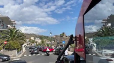 Palmiye ağaçlarının kesişimindeki otobüs vitrininden manzara düşük binalar şehir mimari otobüsü geçiyor yabancılar İtalya 'yı ziyaret ediyor Sicilya Katanya 11.23.2024