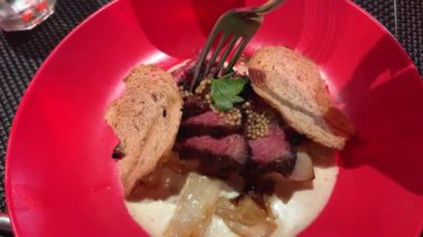 Kırmızı tabakta orta pişmiş kızarmış et yiyen kadın bir çatalla lezzetli bir barbekü yiyor. Yüksek kalite 4k görüntü