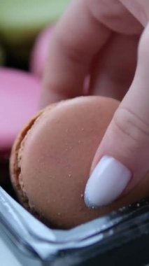 Altı paket badem kurabiyesi yeşil pembe ve çikolatalı kadın eli tatlıyı seçiyor. Yüksek kalite 4k görüntü
