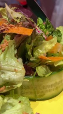 Salatalık, havuç turpu ve marul yapraklı salata. Kadın, çatal, kırmızı manikür ve bıçakla bir parçayı kesiyor. Yüksek kalite 4k görüntü