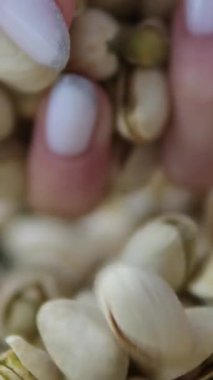 Ağır çekimde çalışan adam arka planda beyaz kaseden kavrulmuş tuzlu şam fıstığı alır. Yüksek kalite 4k görüntü