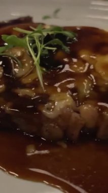 Orta pişmiş ızgara fileto biftekler yeşil çiçek süsüyle birlikte beyaz tabakta servis ediliyor. Tuz kristalleriyle tatlandırılmış iki parça et. Karanlık bir restoranda orta pişmiş et.