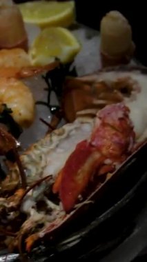 Buzlu deniz ürünleri tabağı şenlikli ıstakoz ve istiridye, yengeç, istiridye, istiridye, karides ve kerevit içeren deniz ürünleri tabağı yukarıdan çekilmiş beyaz masa örtüsü.