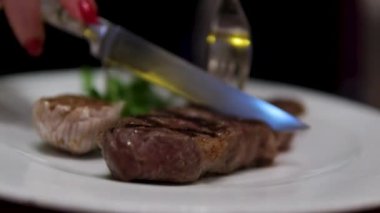 Şef taze ızgara et dilimliyor. Mutfaktaki ahşap kesme tahtasının üzerinde bıçakla. Yemekler yakınlaştırılıyor. Yüksek kalite 4k görüntü