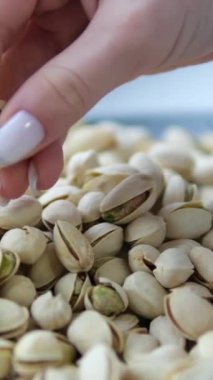 Beyaz manikürlü kadın elleri pencere kenarındaki siyah tabakta taze tuzlu fıstıklar açıyor. Yüksek kalite 4k görüntü