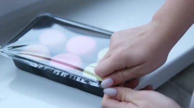 Alıcılar raftan plastik kaplarda bulunan çok renkli badem kurabiyelerini alıyorlar. Lokantada tatlı, hazır yemek. Evde yemek pişir. Yüksek kalite 4k görüntü