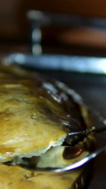 Dorado balığı, brokoli ve yumurtalı turta beyaz bir tabakta sunuluyor. Çatal ve bıçak kullanarak, turtanın bir kısmı tatmak için kesilir. Hamurda pişmiş balık