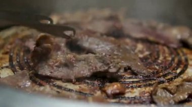 Izgara pastırma şeritleri cızırdayan iyiliğin özünü yakalar ve yok edilmeye hazırdır. Izgara domuz pastırması, yakın plan. Klasik, dumanlı ve çıtır pastırma. Yüksek kalite 4k görüntü