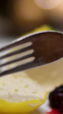 Tabakta bir çatalla limonlu cheesecake yiyorum. Yüksek kalite 4k kalite ayaklı kek biçimli limonlu cheesecake