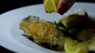 Kadın El, Restoranda İstiridye Masası 'ndan Aldı. Siyah desenli arka planda Limonlu Yarım Kabuklu Taze Çiğ İstiridye. Top View, yakın çekim. Sağlıklı deniz ürünleri yemeği. Yüksek Protein 