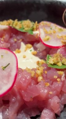 Servis tabağında mango, peynir ve roka ile taze çiğ ton balığı salatası. Keto ya da paleo diyetleri için mükemmel. Sağlıklı ve protein dolu bir yemeğin üst görüntüsü. Siyah tabaktan kaşık çiğ ton balığı salatası.