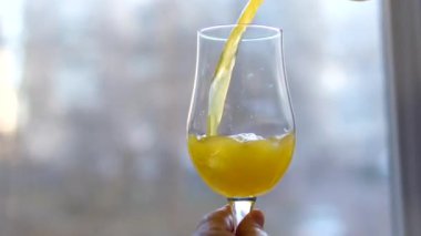 Stüdyodaki açık beyaz ekranda bir bardağa dökülen portakal suyuna yakın çekim. Yüksek kalite 4k görüntü