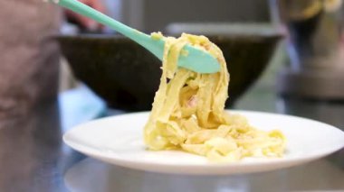 Kapalı ve seçici 4K 'lık bir grup insan, çatal ve kaşık kullanarak beyaz tabakta servis edilen kremalı ve lezzetli İtalyan spagettisiyle restoranda akşam yemeği yiyor. 4k
