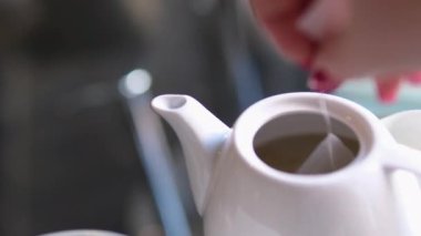 Çay poşetlerini çaydanlıktan kaldırın. Çay poşetini beyaz bir çaydanlığa koy. Yüksek kalite 4k görüntü