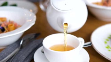 Çay Saati 'nin Sade Zarafeti Pürüzsüz Bir Çaydanlık Çayı İzliyor. Kahvaltıda arka planda avokado ve makarna servis edilir.
