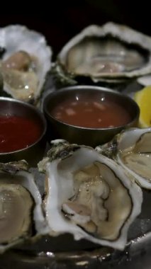 Bolca ezilmiş buz, bir düzine açık istiridye, limon dilimleri ve şarap sirkesi sosuyla dolu metal kırsal tepside manzara. Nefis bir şekilde dizayn edilmiş soğuk deniz ürünleri lezzetleri. 