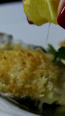 Kadın El, Restoranda İstiridye Masası 'ndan Aldı. Siyah desenli arka planda Limonlu Yarım Kabuklu Taze Çiğ İstiridye. Top View, yakın çekim. Sağlıklı deniz ürünleri yemeği. Yüksek Protein 