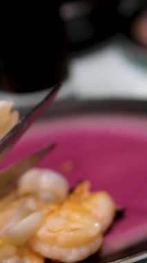 Restoran masasında servis edilen ızgarada pişmiş deniz ürünleri tabağını kesen kadınların yakın çekim görüntüleri. Yüksek kalite 4k görüntü