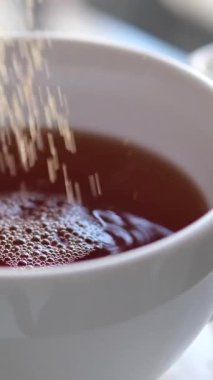 Siyah kahveye şeker koyan koyu kamış şekeri. Şeker kahve fincanına düşer. Kafein Bağımlısı Hurda Yiyecekler. Sağlıksız yeme, diyabet, obezite, kalp hastalığı kavramı. 4k