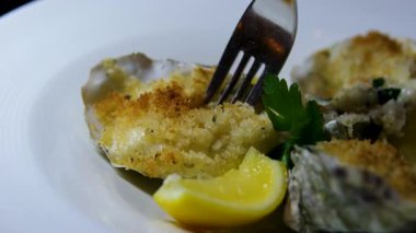 Elinde taze çiğ istiridye tutan adam elinde sıkılmış limon suyuyla taze taze istiridye açtı ve tatmak için çatala sardı, deniz ürünleri şarküterisini kapadı. Balık pazarından taze açılmış istiridye. 4k