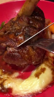 Kırmızı tabakta çatal ve bıçakla kesilmiş patates püresi ve kuzu budu. Yüksek kalite 4k görüntü