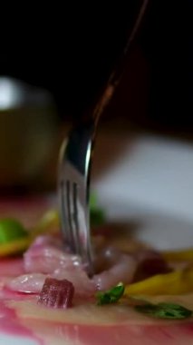 Kadın siyah seramik tabağa ton balığı carpaccio pişirirken taze çiğ ton balığı filetosu koyar. Yüksek kalite 4k görüntü