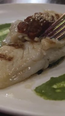 Ağız sulandırıcı kızarmış balık, çıtır çıtır kabuklu ve otlu, baharatlı soslu beyaz bir tabakta servis edilir, enfes bir mutfak keyfi ortamı yaratır. Yüksek kalite 4k görüntü