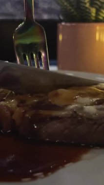 Bir şef, siyah bir arkaplana karşı çatal kullanan biftek parçalarının üzerine domates sosu koyar. Yiyeceğe yakın çekim. Yüksek kalite 4k görüntü