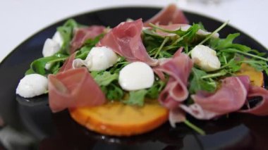 Yerel restoranlarda geleneksel İtalyan yemeği Prosciutto mozzarella roka, Persimmon salatası aperatifleri ve aperatifleri, Akdeniz mutfağı lezzeti. Yüksek kalite 4k görüntü