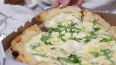 Zeytin, roka, jambon ve erimiş peynirle kaplı bir dilim pizzayı tutan bir el parşömen kağıdında servis edilir. Lezzetli bir aperatif veya yemek için mükemmeldir. Yüksek kalite 4k görüntü