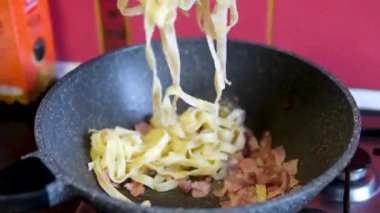 Pastırmalı makarna pişirme şefi domuz pastırması ya da İtalyan usulü guanciale ya da İtalyan usulü makarna için tavada pancetta pişiren bir kadın. Yüksek kalite 4k görüntü