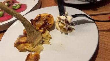 Kadın çatal ve bıçakla doldurulmuş enginardan bir parça alıyor ve yiyor. Sigacik 'teki açık hava restoranı. İzmir, Türkiye. Yüksek kalite 4k görüntü