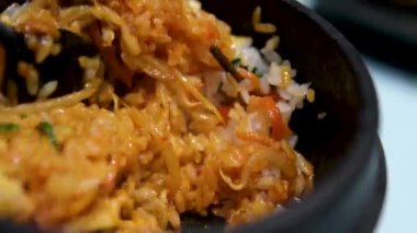 Yumurta kızartılmış pirinçli, havuçlu ve yeşil bezelyeli, tavada pilavı karıştırmak için spatula kullanılıyor. Yüksek kalite 4k görüntü