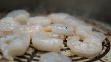 Karidesleri ızgara yapan bir adam dışarıda maşa çeviriyor, kapanıyor, gün batımında deniz kıyısında piknik yapıyor. Yüksek kalite 4k görüntü