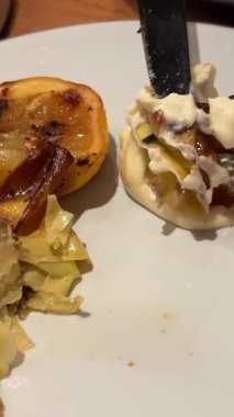 Kadın çatal ve bıçakla doldurulmuş enginardan bir parça alıyor ve yiyor. Sigacik 'teki açık hava restoranı. İzmir, Türkiye. Yüksek kalite 4k görüntü