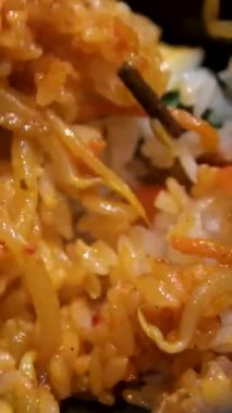 Yumurta kızartılmış pirinçli, havuçlu ve yeşil bezelyeli, tavada pilavı karıştırmak için spatula kullanılıyor. Yüksek kalite 4k görüntü