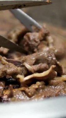 Kore usulü ızgara domuz eti pişirirken yakın çekim ve ızgarada et kesmek için makas kullanın. Izgarada domuz göbeği, tavada domuz eti pişirme, Kore usulü barbekü. Yüksek 