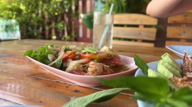 Derin bir kasede servis edilen karides salatası. Taze yeşillikler, salatalıklar, kiraz domatesleri ve yumuşak, ızgara karides ve meze ile süslenmiş fındıklı fındıklar servis ediliyor. Sebze çatallı deniz ürünleri.